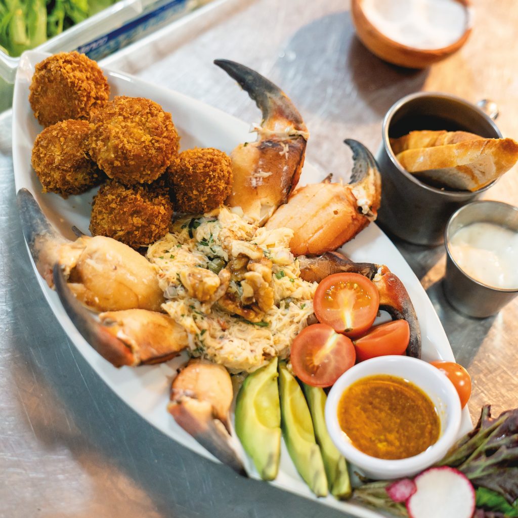 Plato con bolitas de mariscos fritas y crujientes acompañadas de pinzas de jaiba frescas en el restaurante Mesa Incógnita, Valdivia.